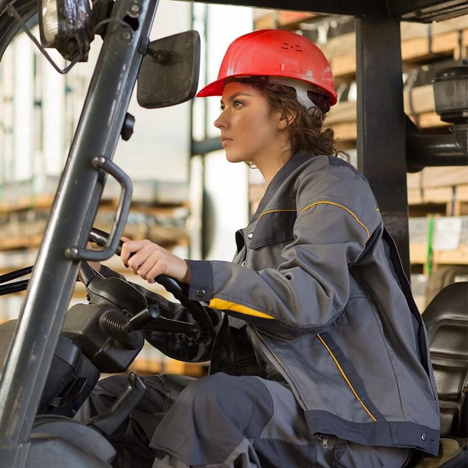 Woman forklift driver working in a warehouse with industrial equipment
